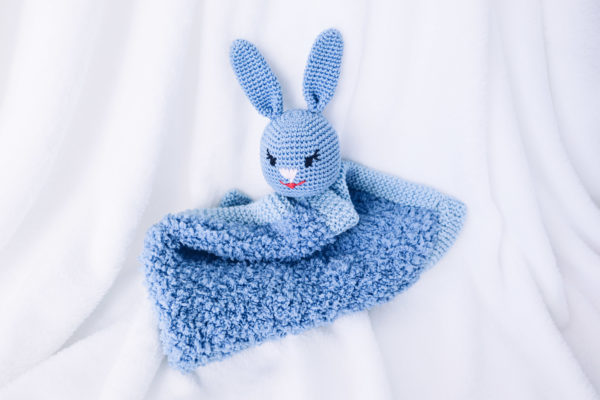 Un doudou super moelleux avec une tête de lapin crocheté et tricoté de couleur bleu.