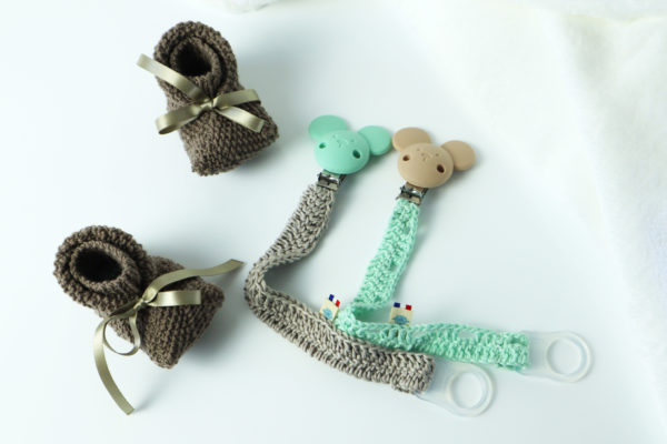 Une paire de chausson marron 3/6 mois deux accroches tétine en laine et silicone marron et vert eau.